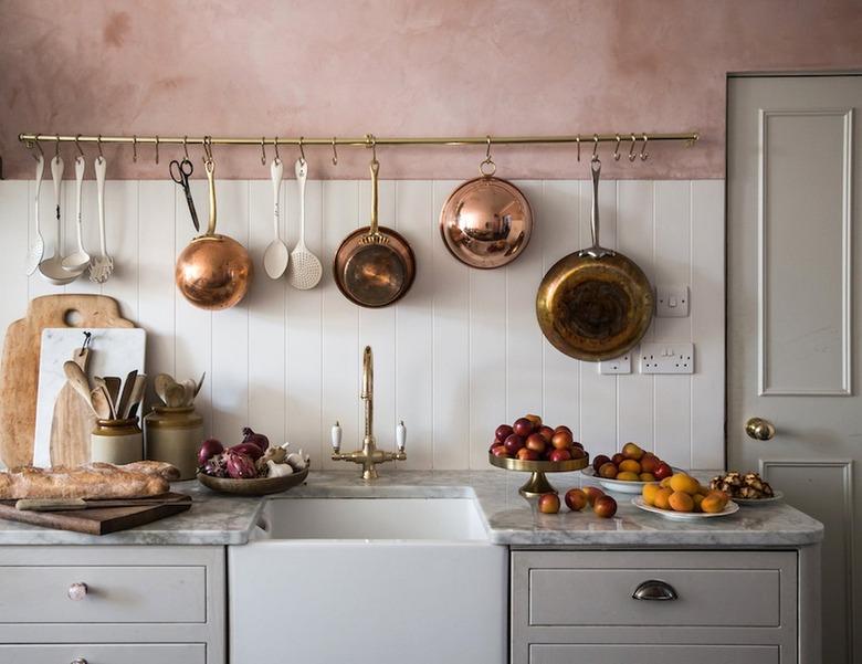 Small kitchen with grey cabinets, white backsplash and pink plaster walls.