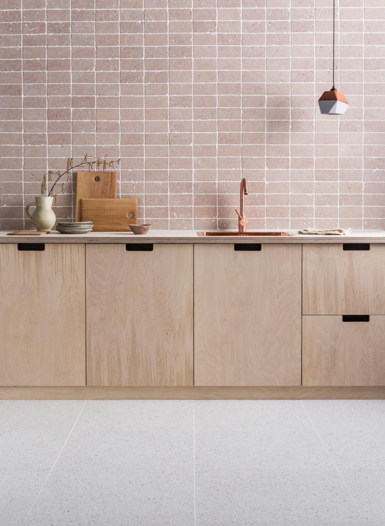 kitchen space with light terrazzo floor, wood cabinets, and brown backsplash