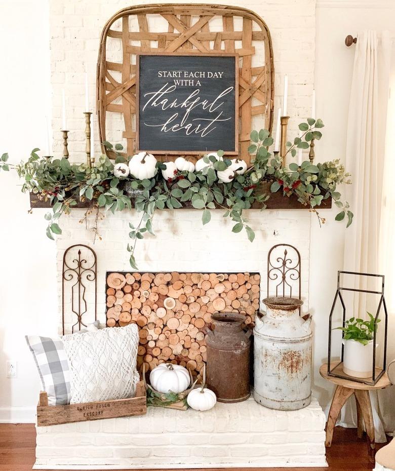 Rustic fall decor on fireplace mantle with tobacco basket and greenery