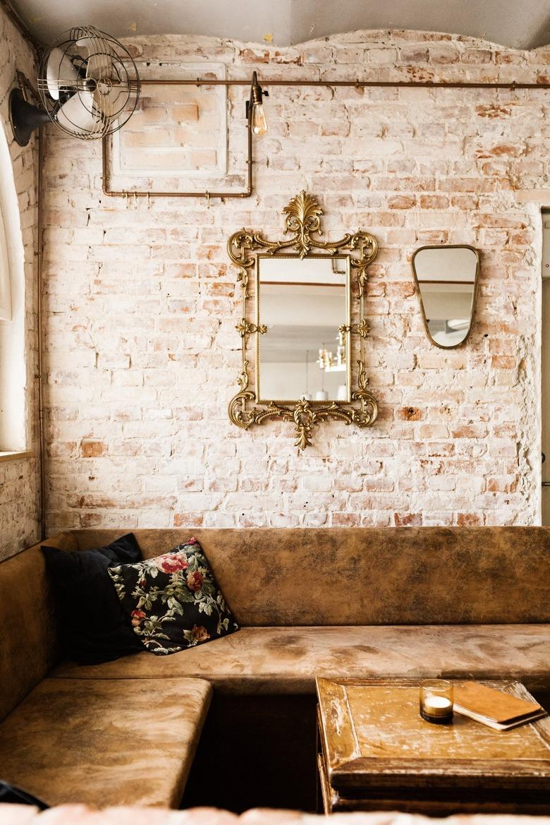 rustic industrial decor with brown leather booth against light brick wall with mirrors