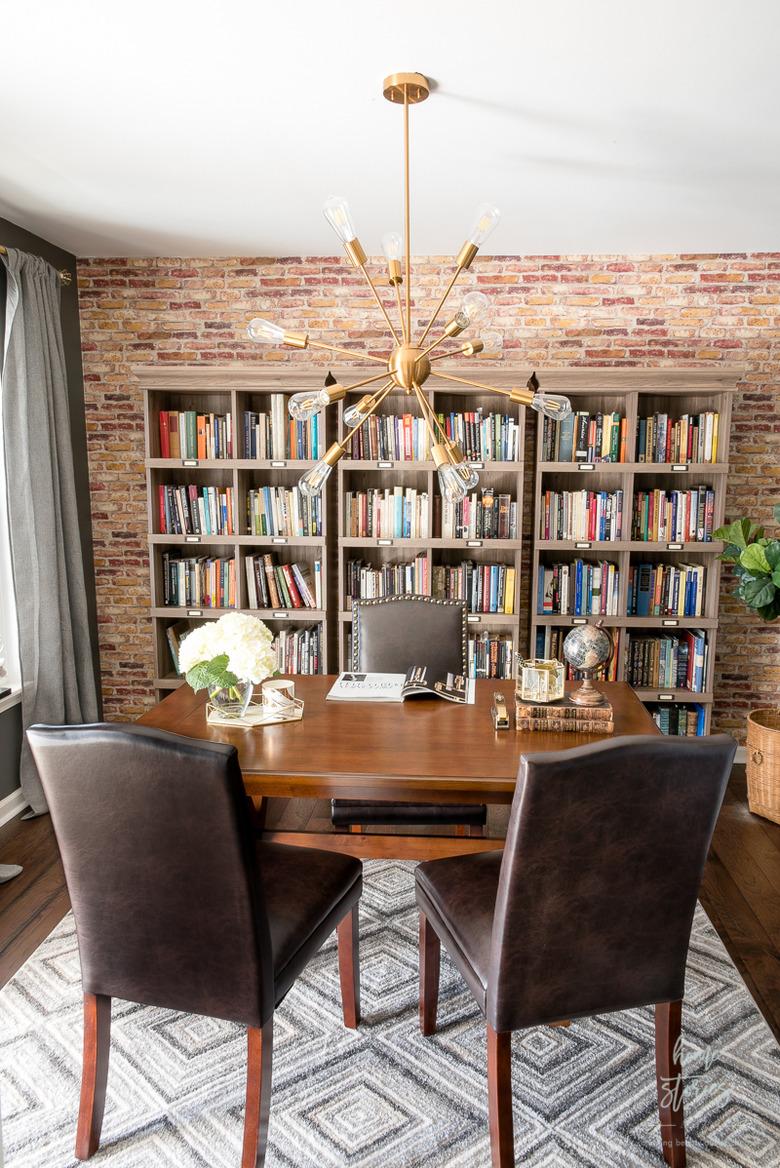 Rustic office with brick wall and wood table with leather chairs