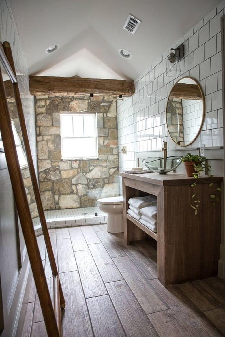 rustic shower idea with exposed wood beam and stone accent wall