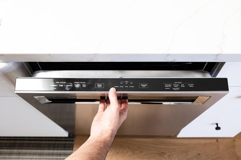 A person opening a silver dishwasher