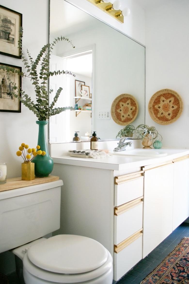 self-rimming bathroom sink in a boho rental with frameless mirror and white vanity cabinet