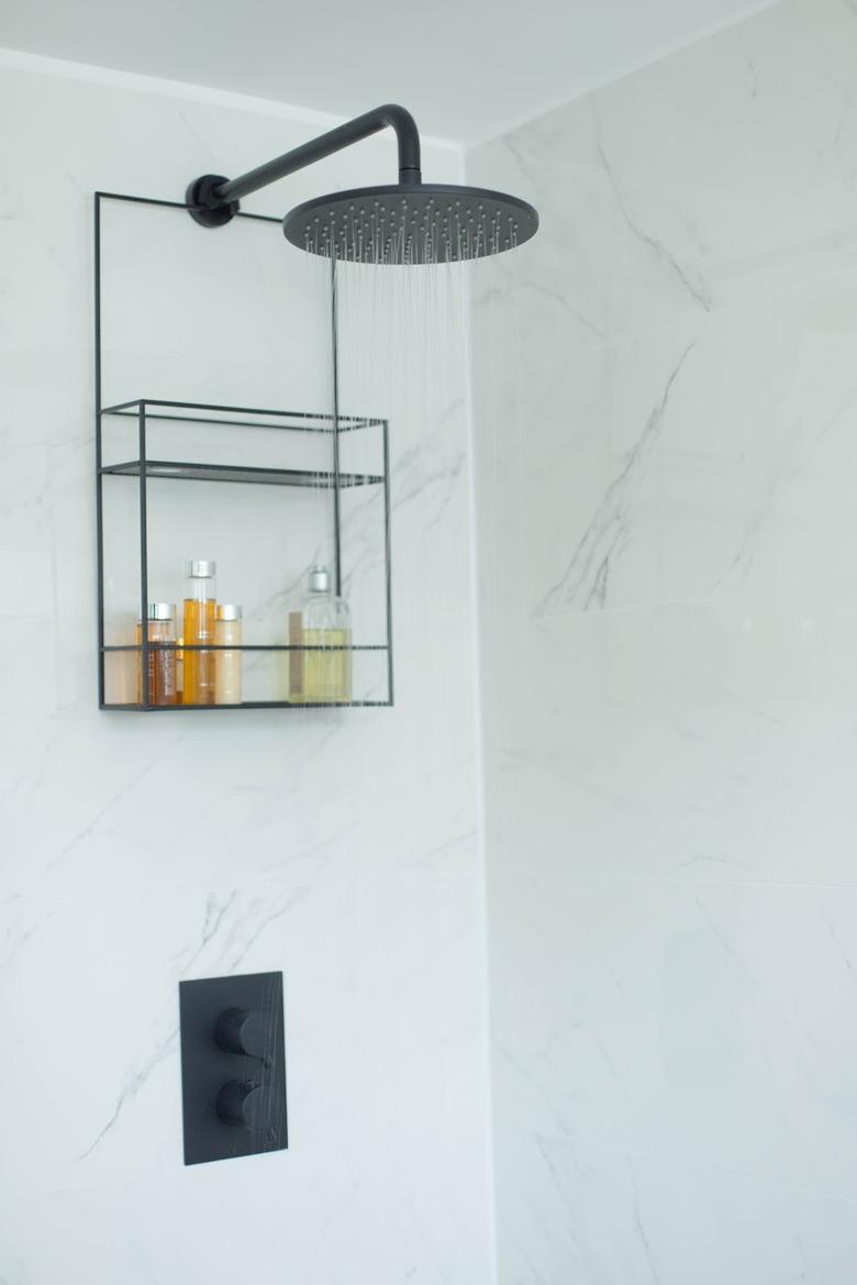 marble shower storage ideas with black fixtures and shower caddy