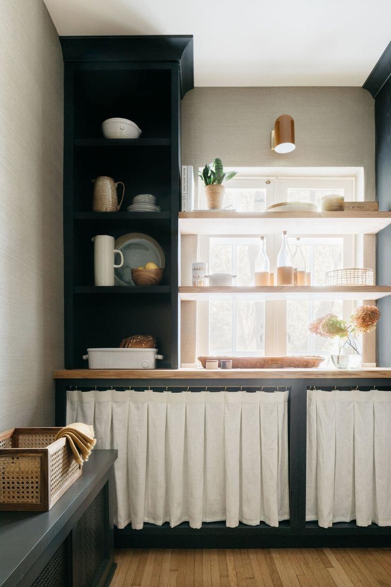 Kitchen with dark open cabinets and pleated fabric covering lower cabinets.