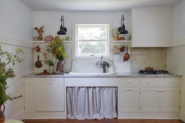 White farmhouse kitchen with linen curtains under sink.