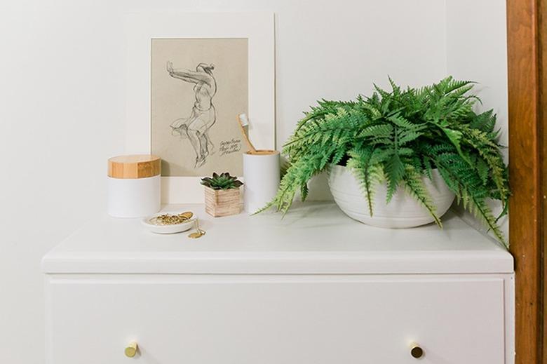 small bathroom wall art with several toiletry containers on top of a dresser