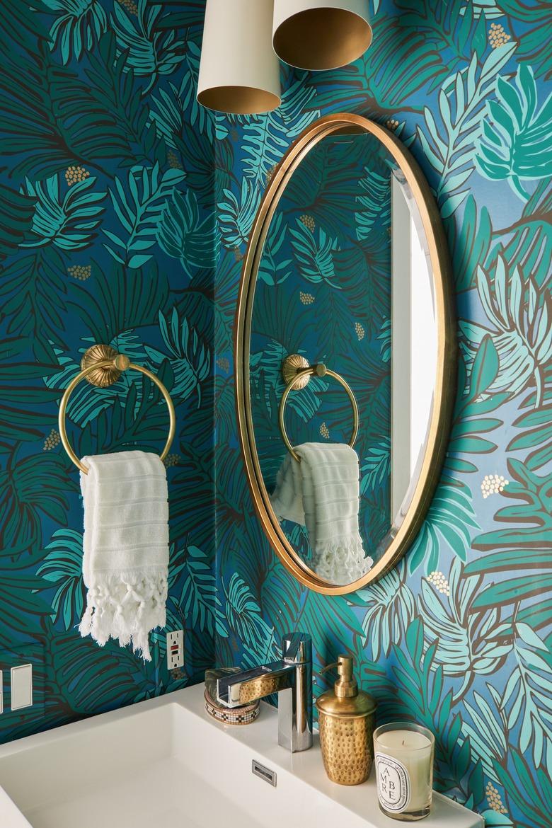 small boho bathroom with green floral wallpaper and brass fixtures