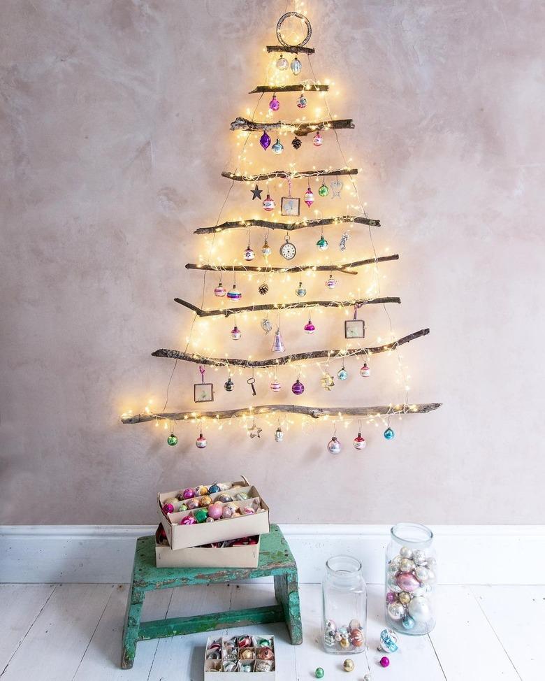 tree branches and lights on wall with stool and books nearby