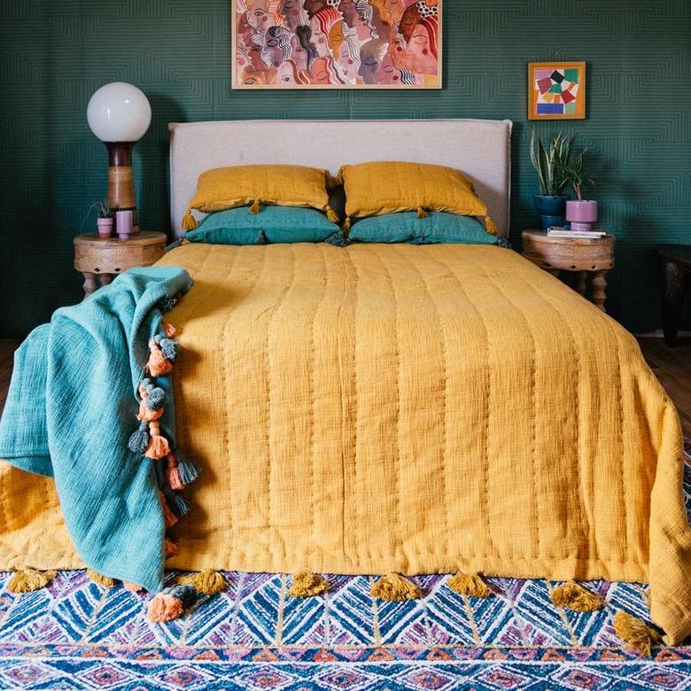 bed with tumeric colored quilt