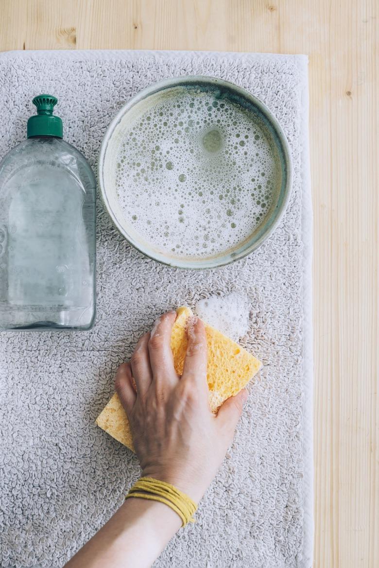 using a sponge and a solution of dish soap and water to clean  carpet stain