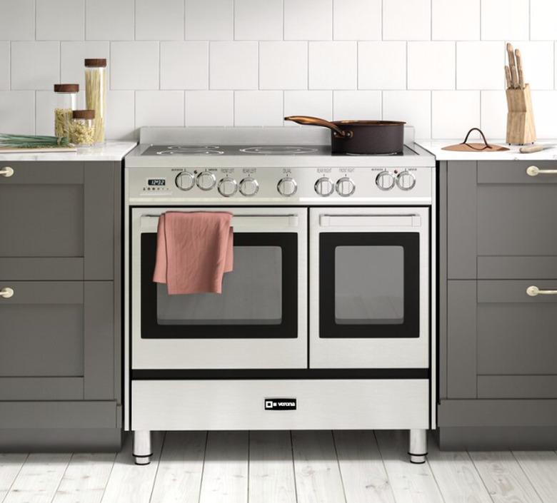 Kitchen with stainless steel electric stove, dark gray cabinets, white tile backsplash.