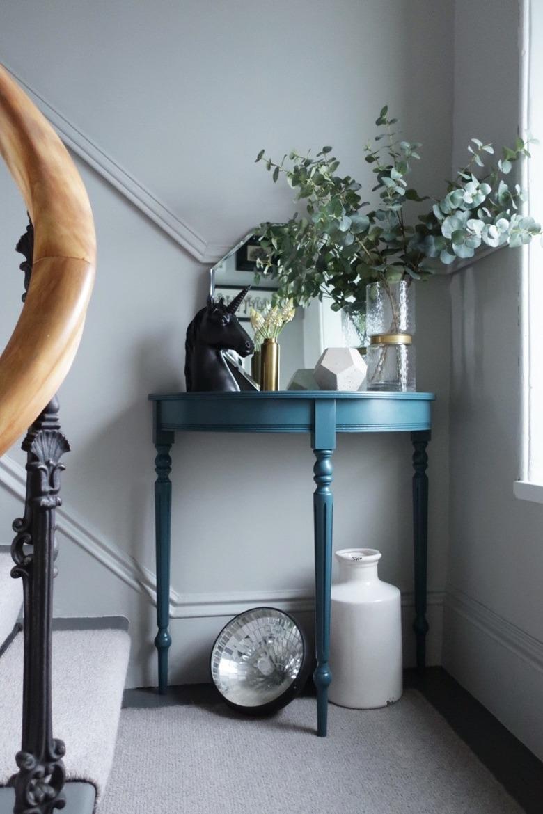 Blue console table with decor along stairs