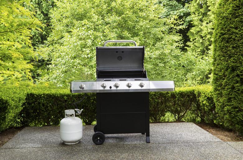 Large outdoor bbq cooker with lid in open position on home concrete patio