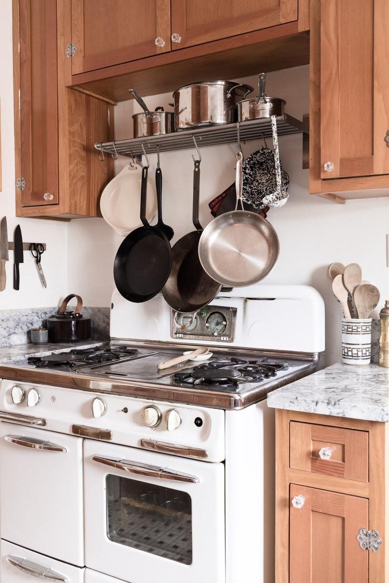 pans hanging over gas stove in a minimalist kitchen