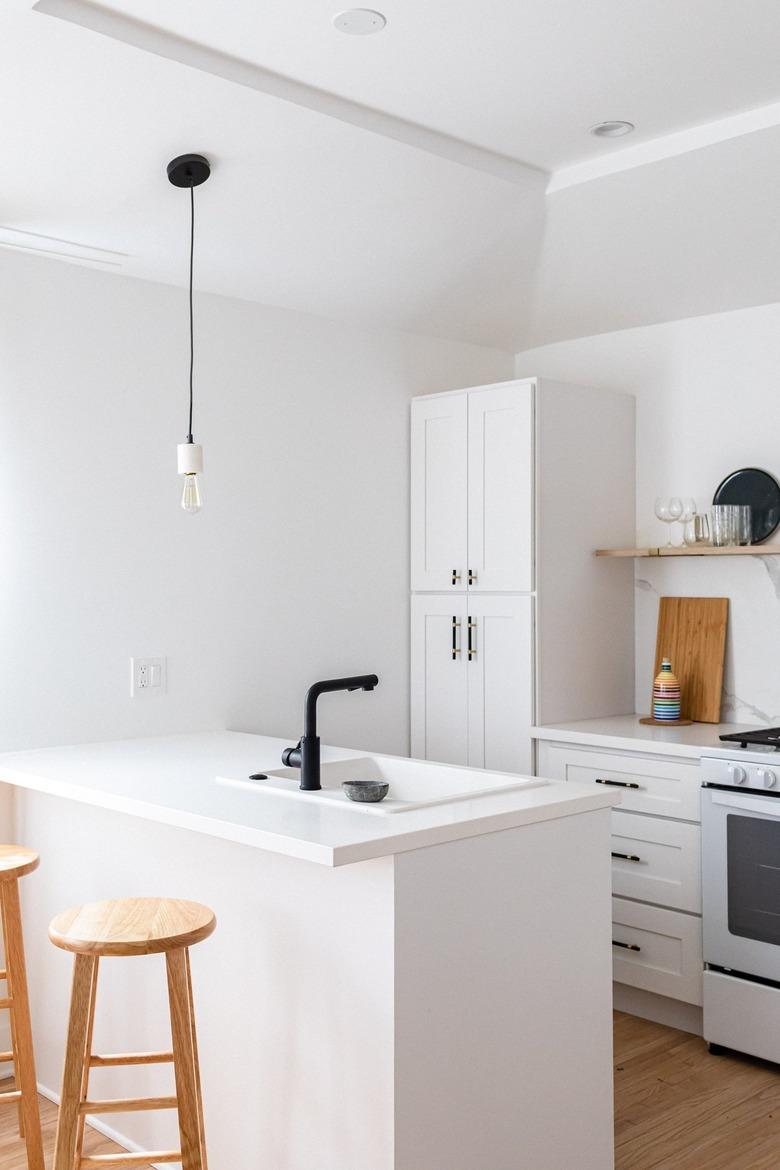 A white walled kitchen with white cabinets and counters and black accents