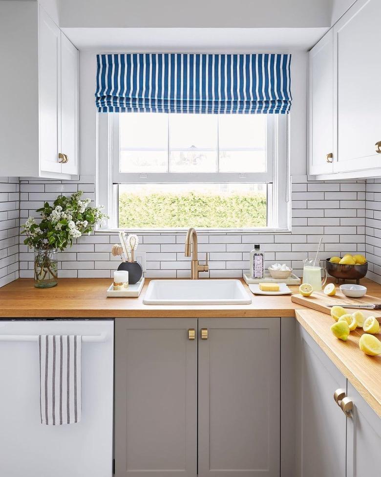 modern kitchen with two-toned cabinets and a striped roman shade