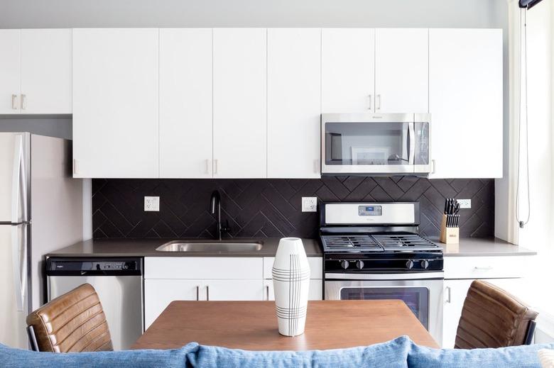 modern kitchen with white cabinets and dark backsplash