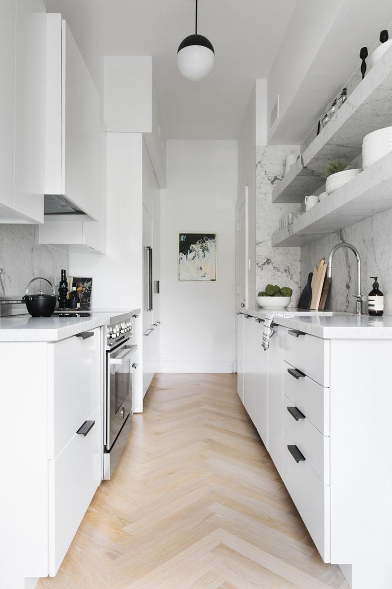 white kitchen with black hardware and marble shelves