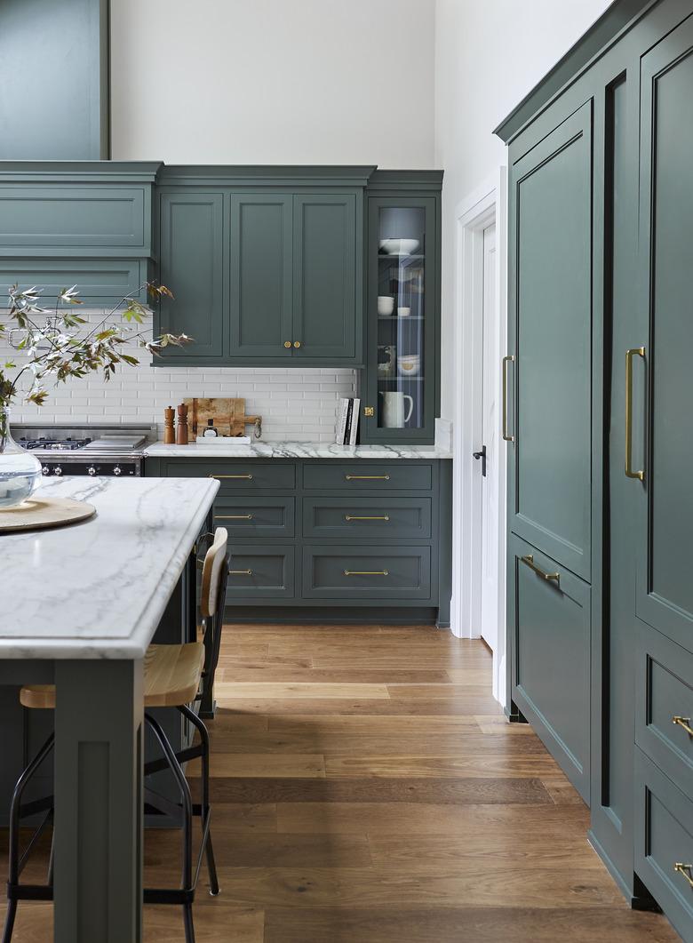 Teal kitchen idea with painted cabinets, hardwood floor, and marble countertops