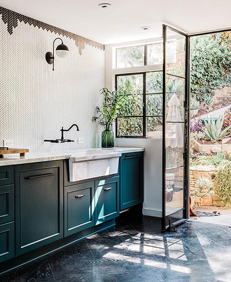 Teal kitchen idea with black and white tile wall and farmhouse sink