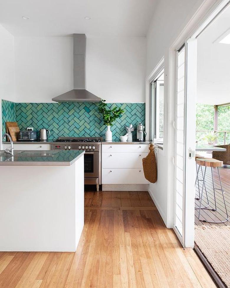 teal kitchen idea with chevron pattern tile backsplash and white cabinets