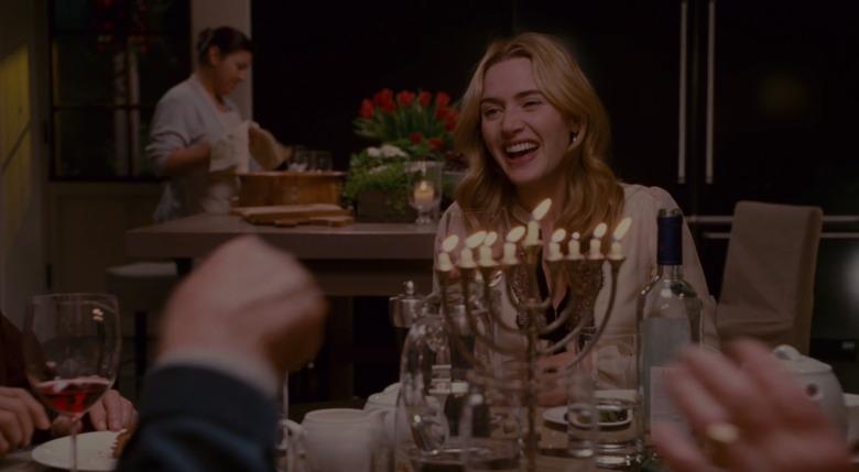 woman laughing in front of menorah, still image from the holiday