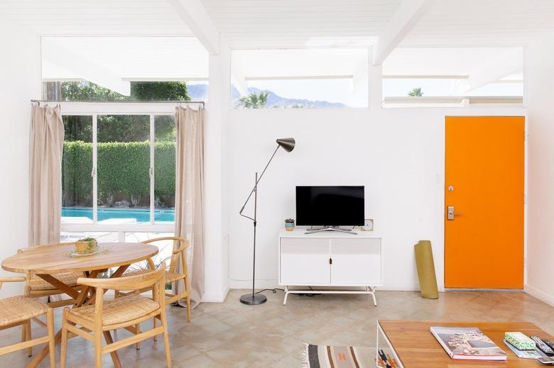 an entry area featuring a white entertainment console, mid-century swing-arm lamp and a bright orange door