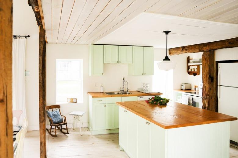 a half-timbered kitchen with a wooden ceiling, a pine-topped island, wood floors, green cabinets, and a wooden ceiling