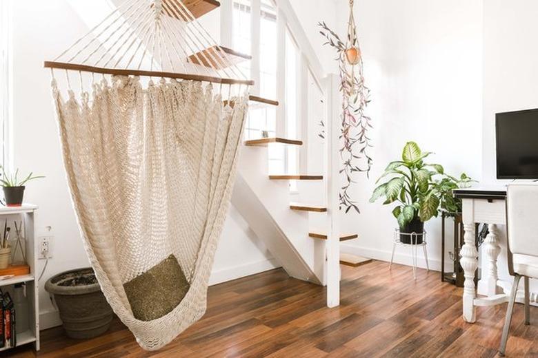 jungalow minimalism in modern apartment stairway with hanging macrame chair and plants