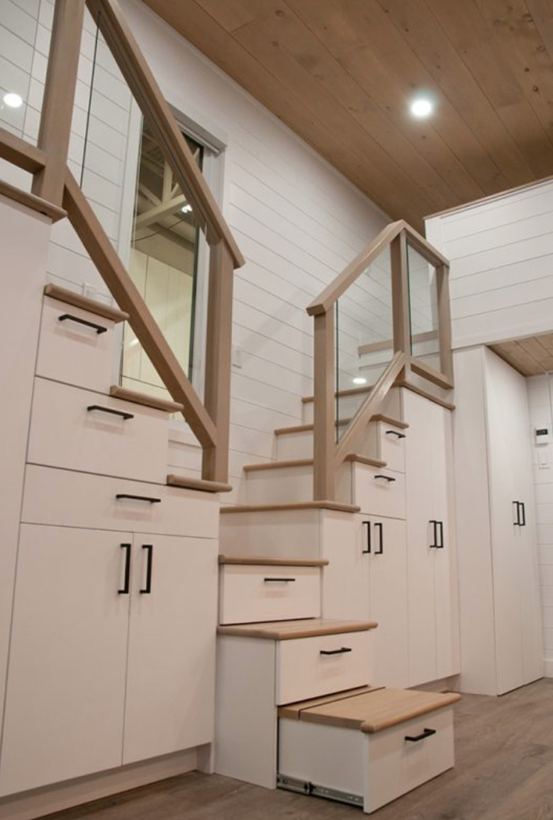 tiny house stairs with white cabinets, light wood floors and hand rails, stairs, wood ceiling, and recessed lighting.