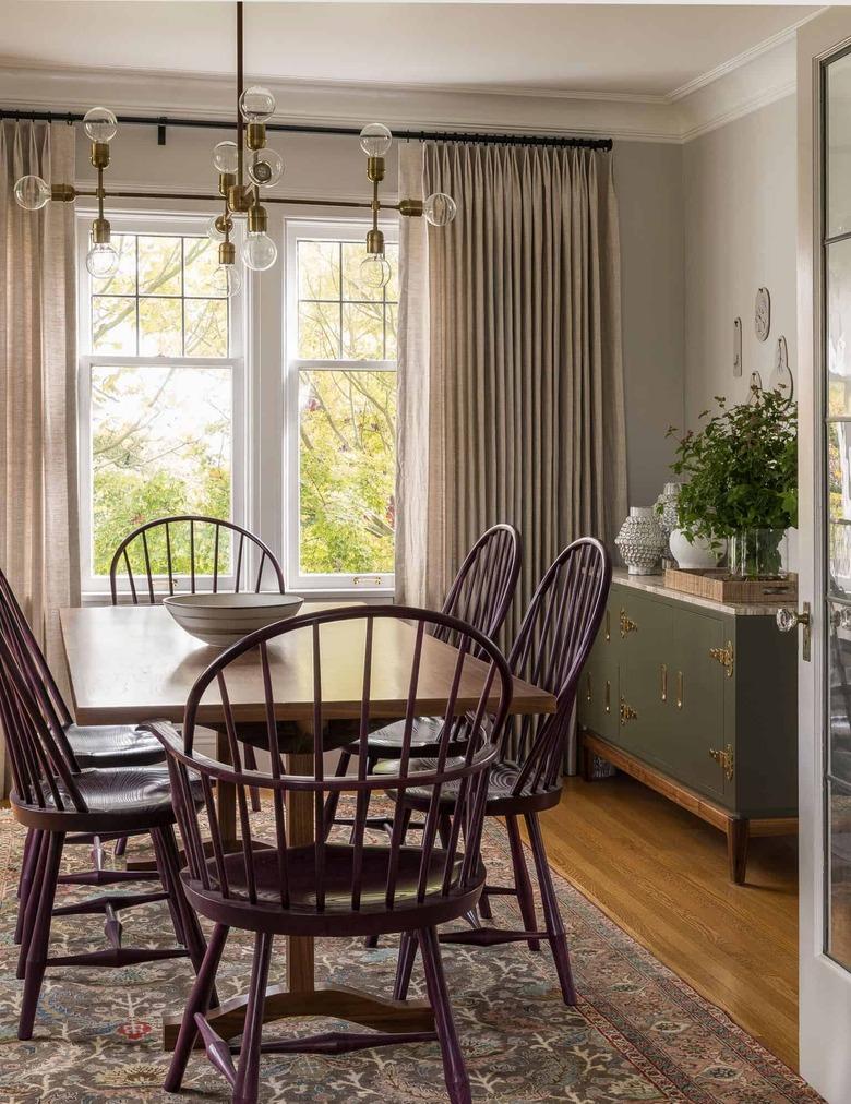 traditional dining room with purple Windsor-style chairs and green storage cabinet