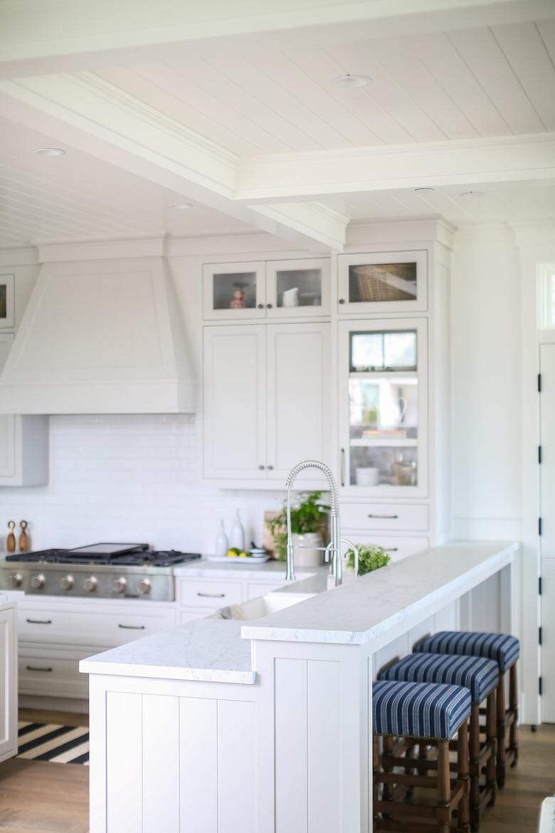 white two-tier kitchen island with striped bar stools