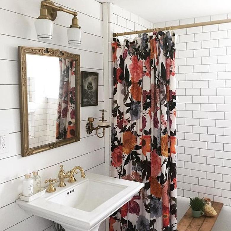 white bathroom with floral shower curtain and pedestal sink