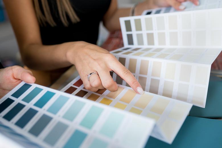 Closeup of two people choosing samples of wall paint. Interior designer consulting a client looking at a color swatch. House renovation concept.