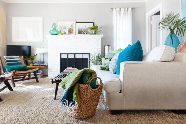 Boho-beach living room with a white brick fireplace, wood furniture, turquoise and green decor, and woven accents.