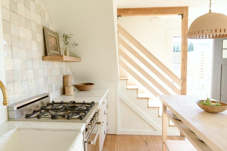 Gas stove and pendant lamp with beige backsplash in kitchen