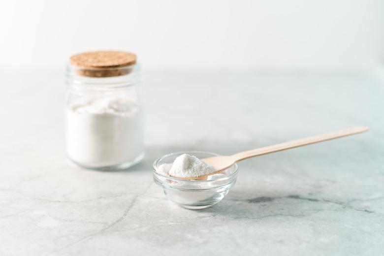 Eco friendly natural cleaners, jar with baking soda, lemon and wooden spoon on marble table background. Organic ingredients for homemade cleaning. Zero waste concept