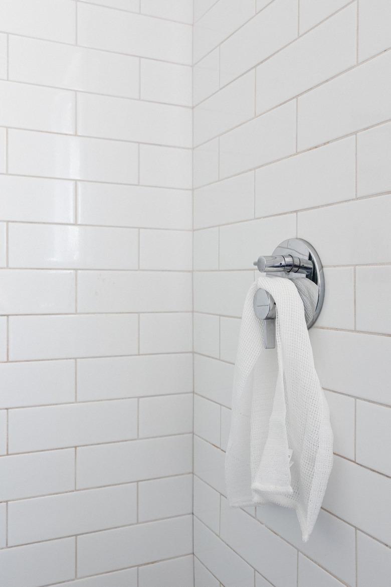 white subway tile with chrome shower handle with white towel