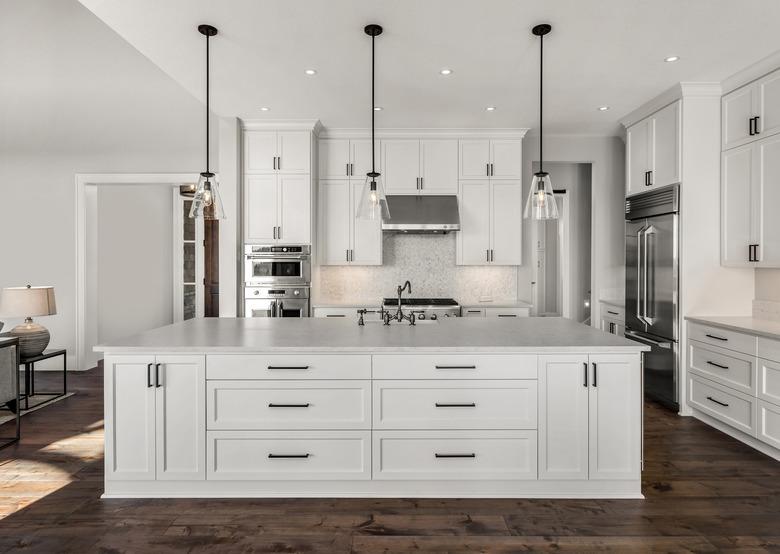 Beautiful kitchen in new luxury home with island, pendant lights, and hardwood floors.