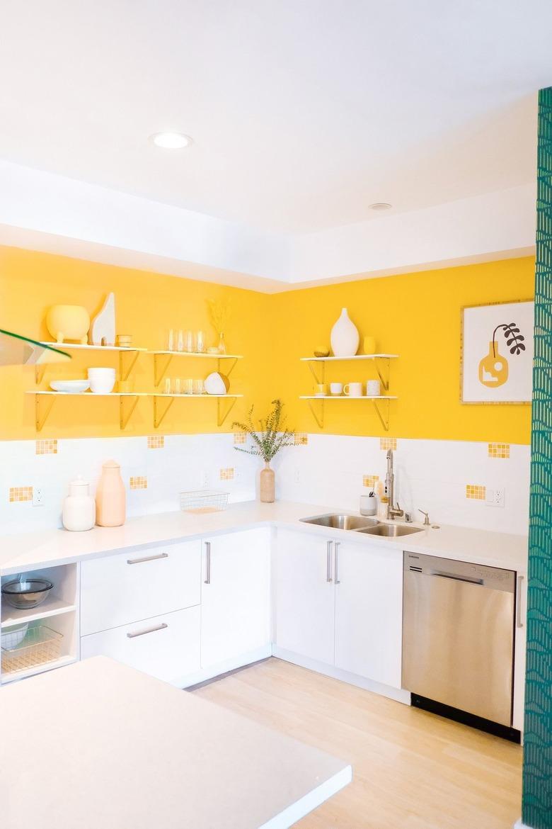 Bright kitchen with yellow wall paint and white cabinets.