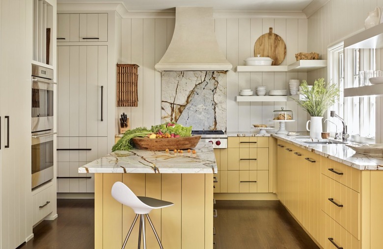 Rustic kitchen with yellow wood panel cabinets, marble countertops and open shelving.