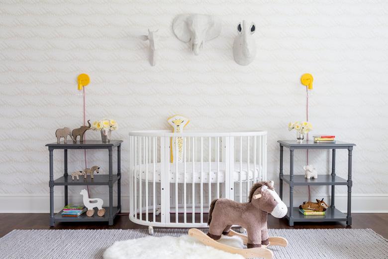 yellow nursery idea with yellow wall sconces and white crib and stuffed animals mounted to wall