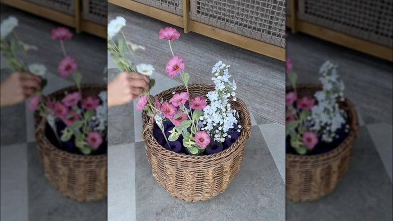 a woman placing faux flowers into pool noodle holes in a basket