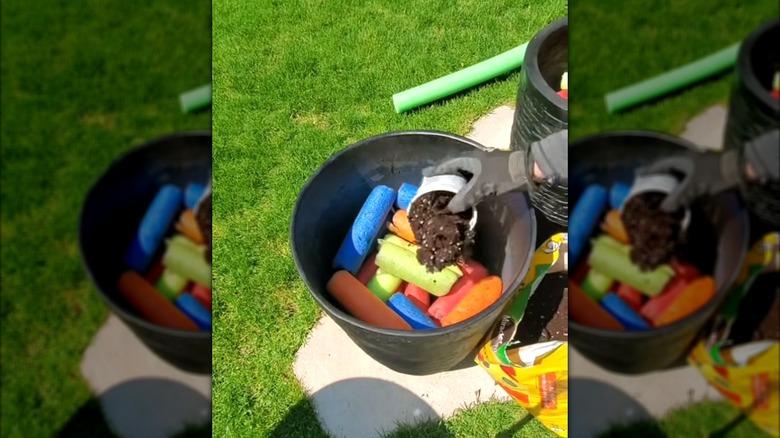 a person pouring soil into a pot with cut up pool noodles