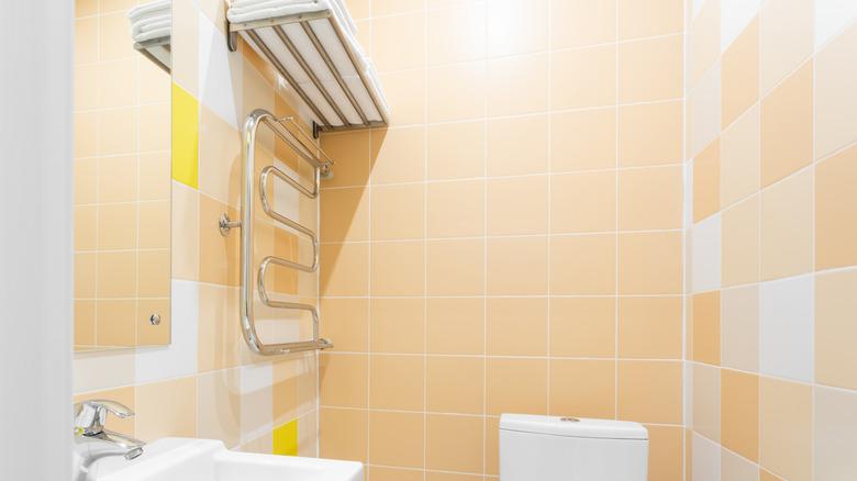 peach colored tiled bathroom with metal hardware and white sink and toilet