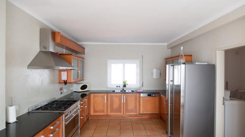 large, barren, outdated kitchen with ugly red wood cabinets