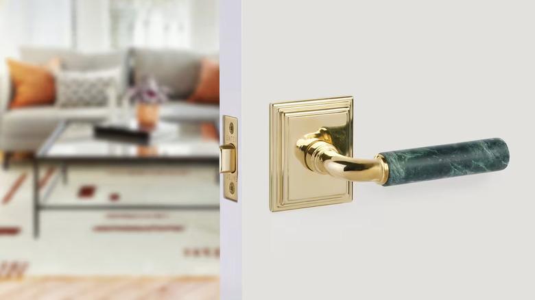 green marble interior door lever with brass rosette on white door that is opening into a living room