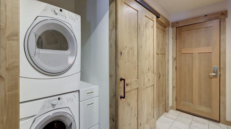 Stacked washer and dryer beside tan-colored cabinetry